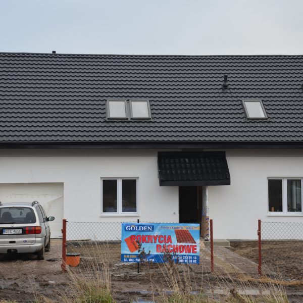 Pokrycie dachu blachodachówką Ruukki Finnera czarna, kontrastujące z jasną elewacją.